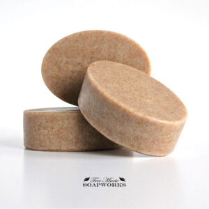 Three oval-shaped artisan soap bars in warm beige with fine brown speckles from ground walnut shells.