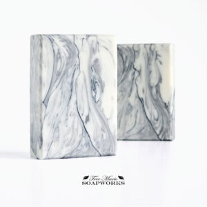 Marble Study artisan soap with flowing gray and black veining on a pale background, shown in two bars.